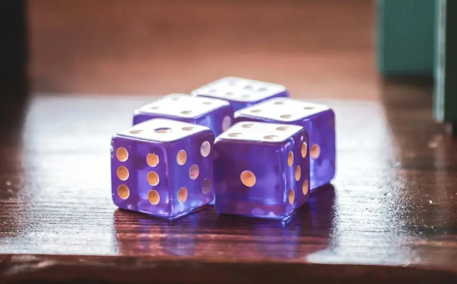 ¿Qué tan probable es que, después de agitar la caja y al tirar los dados todos caigan con el número dos hacia arriba?