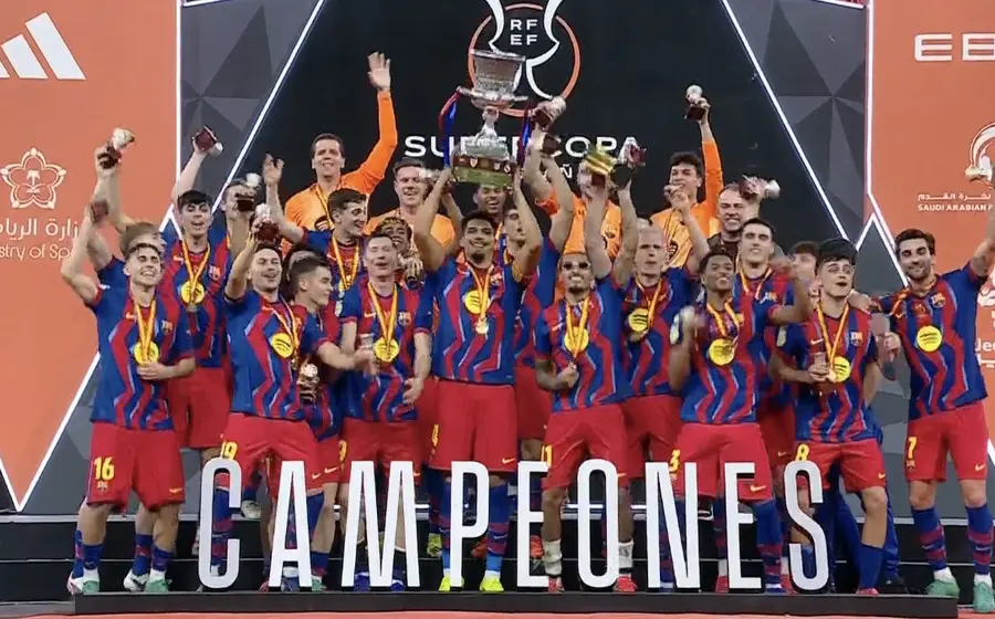 El equipo de fútbol del FC Barcelona celebra su victoria al coronarse como bicampeón de la Supercopa de España en el campo.