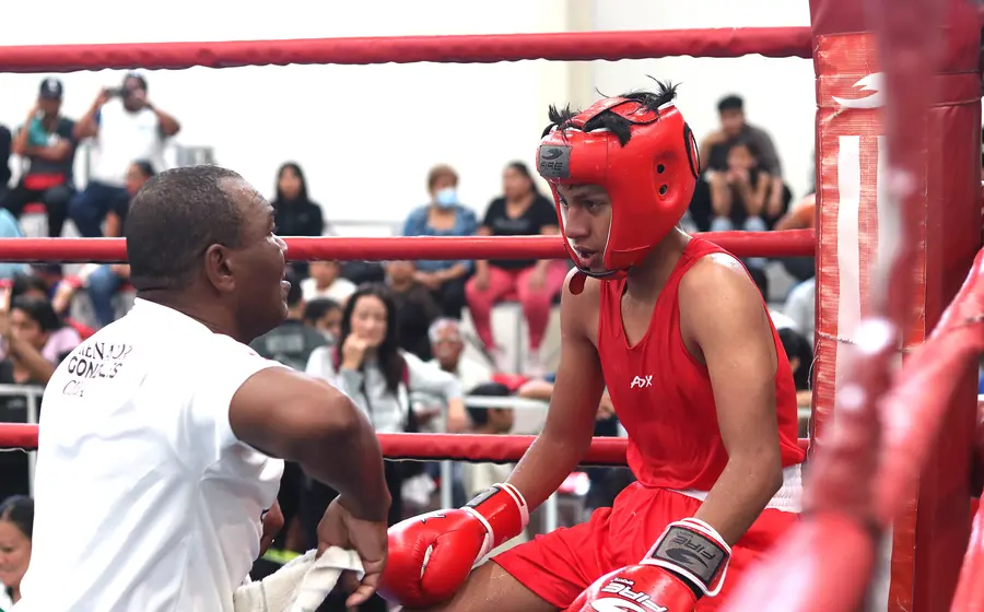 Un atleta de boxeo olímpico se prepara para pelear con gran determinación dentro del cuadrilátero al sonar la campana de inicio.