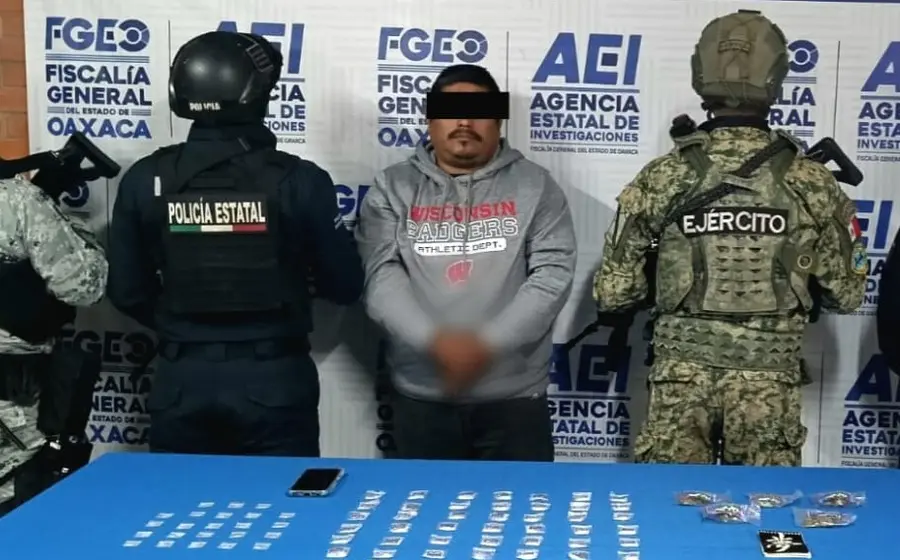 Un hombre detenido por narcomenudeo es presentado por las autoridades junto a los paquetes de droga que le fueron asegurados durante su captura.