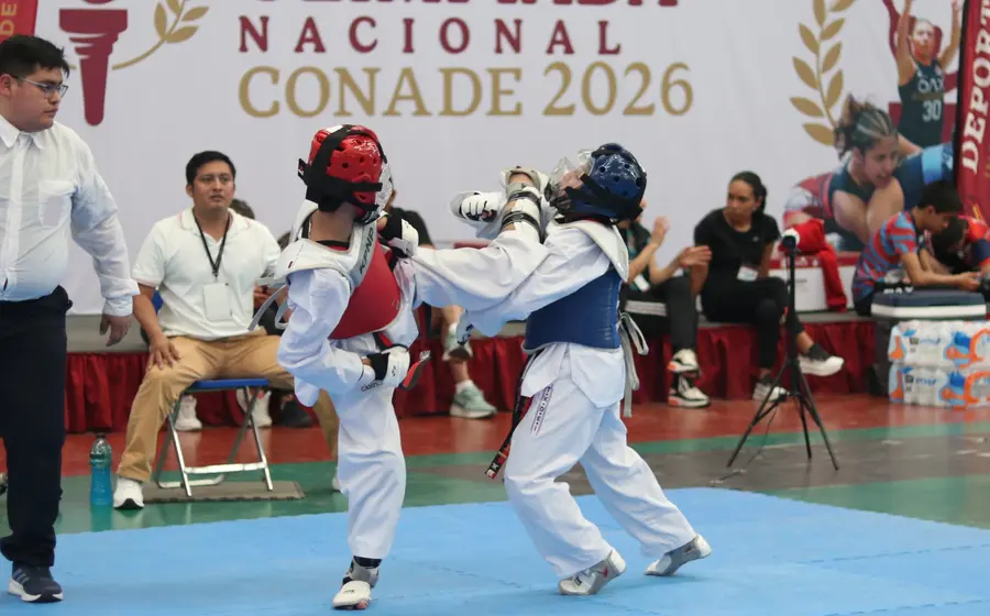 Dos atletas se enfrentan en un duro combate de taekwondo durante el torneo estatal, demostrando su habilidad y esfuerzo en la competencia.