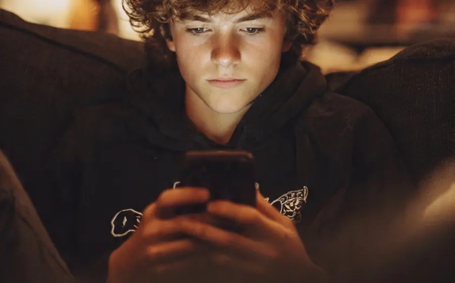 Un joven aislado del entorno mientras utiliza su smartphone, representando el impacto negativo de la tecnología en las competencias de comunicación.