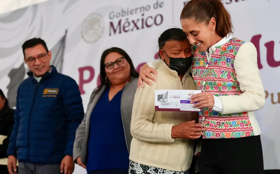 La Presidenta de México entrega una tarjeta del programa Pensión del Bienestar a una mujer, beneficiando a 3 millones de personas en el país.