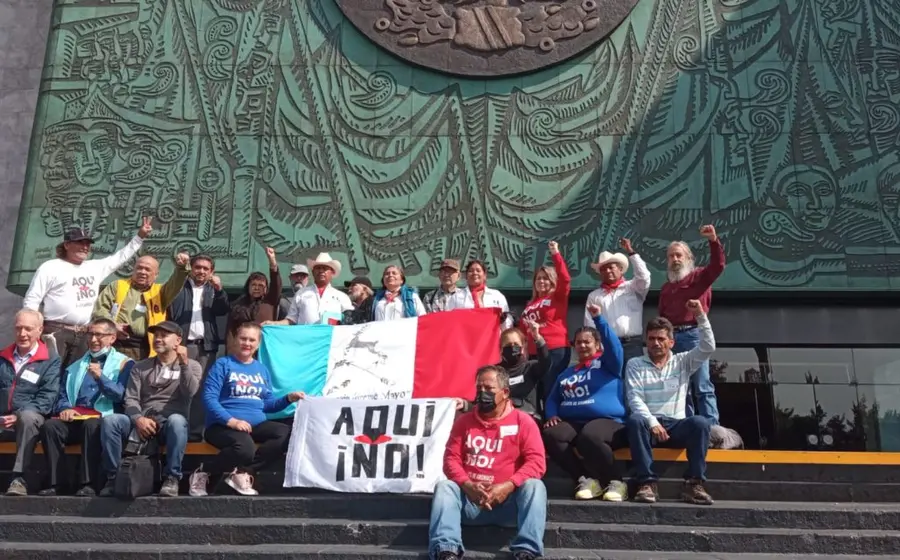 Miembros del movimiento '¡Aquí no!' realizan una protesta en las afueras de la sede del Legislativo federal con pancartas.