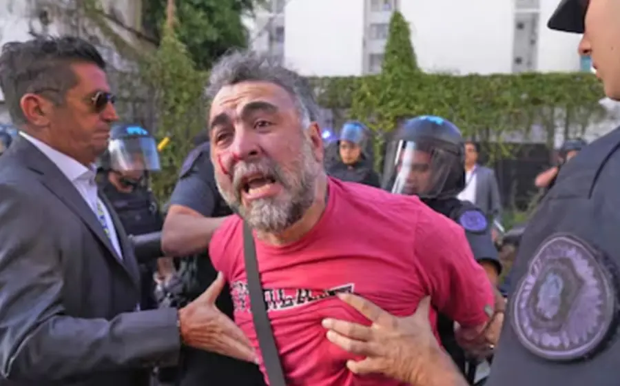 El camarógrafo Facundo Tedeschini es agredido mientras documenta con su cámara la detención de activistas de Greenpeace durante una protesta.