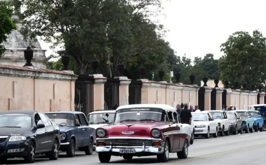 Larga fila de vehículos esperando para cargar combustible en Cuba, ilustrando la escasez y las fallas de transporte advertidas por la embajada de EU.