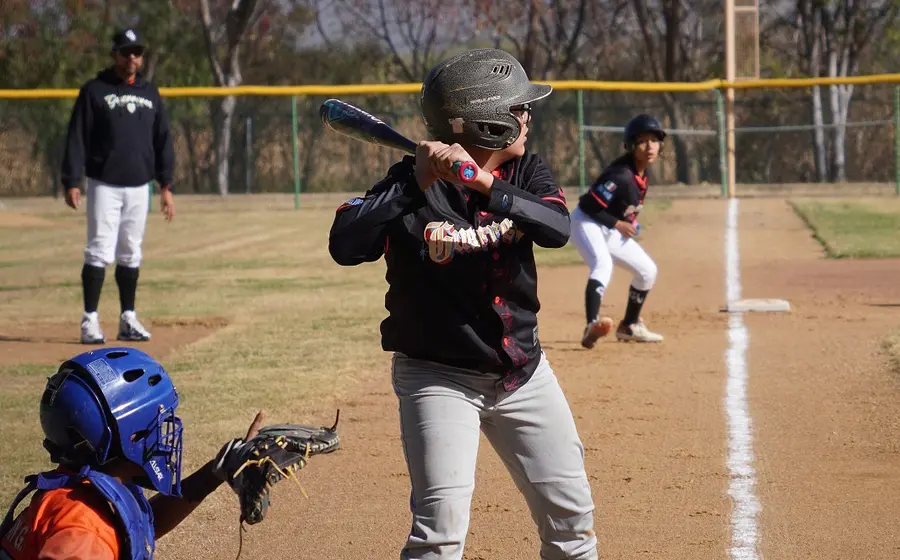 Un jugador de béisbol en plena acción durante el rally decisivo del tercer inning que resultó en una espectacular voltereta en el marcador.