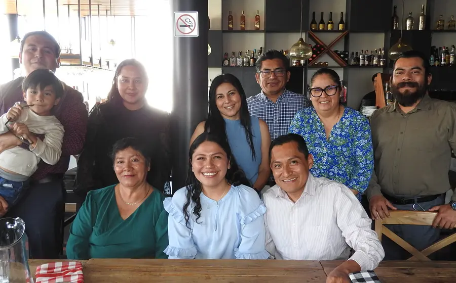 La médico pediatra Dulce Martha Pérez Cruz celebra su exitosa presentación de tesis, sonriendo junto a sus familiares y profesores en Oaxaca.