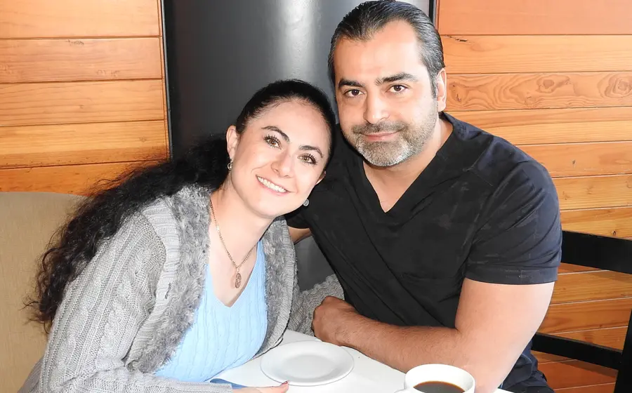 Jenny Kaminski y Hugo Castro posan juntos y sonríen para la cámara mientras disfrutan de un café en un evento social.