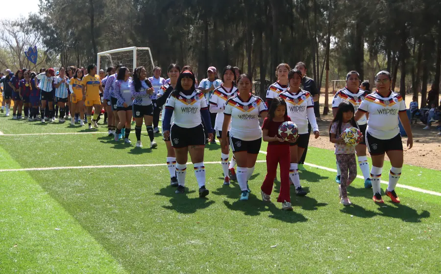 Equipos de la liga de futbol femenil de Zaachila desfilan frente al presídium durante la ceremonia de inauguración del torneo.