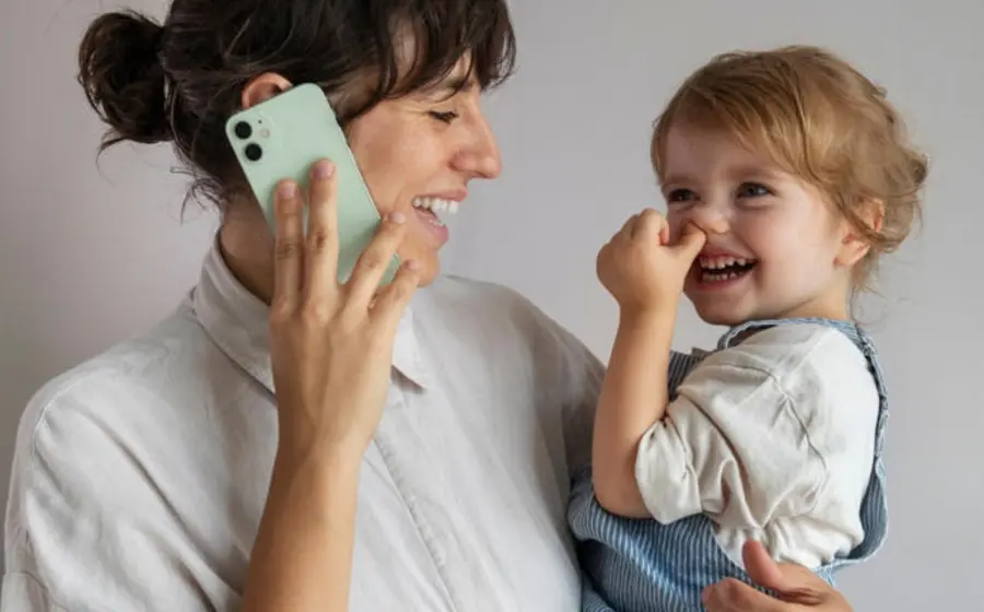 Un niño pequeño se concentra en una pantalla, simbolizando cómo la tecnología puede reemplazar la interacción y presencia de los padres en la infancia.