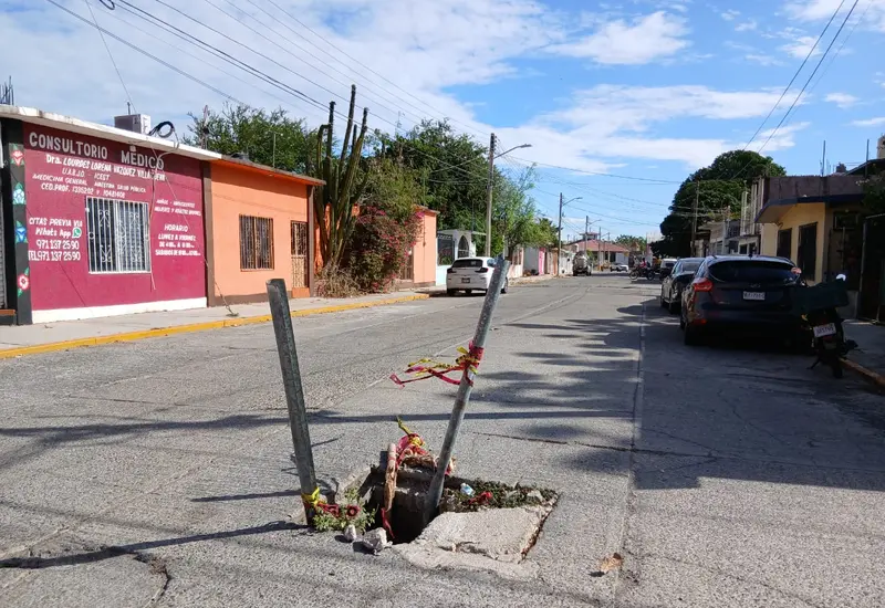Una alcantarilla abierta en Tehuantepec es señalizada con palos y piedras por habitantes para alertar del peligro a transeúntes y automovilistas.
