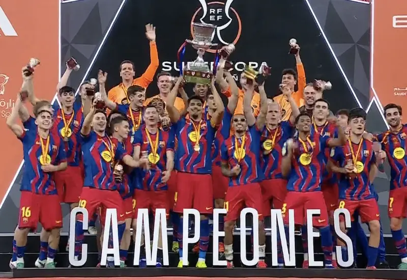 El equipo de fútbol del FC Barcelona celebra su victoria al coronarse como bicampeón de la Supercopa de España en el campo.