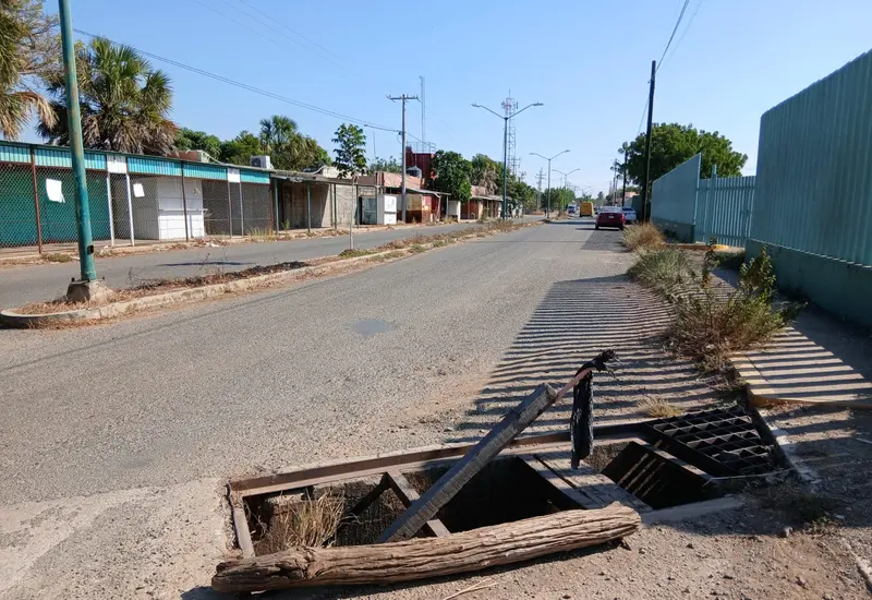 Un tramo de la Avenida Universidad en Tehuantepec con enormes baches que parecen cráteres, mostrando las pésimas condiciones de la vialidad.