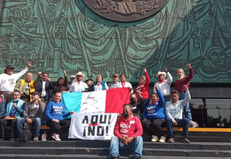 Miembros del movimiento '¡Aquí no!' realizan una protesta en las afueras de la sede del Legislativo federal con pancartas.