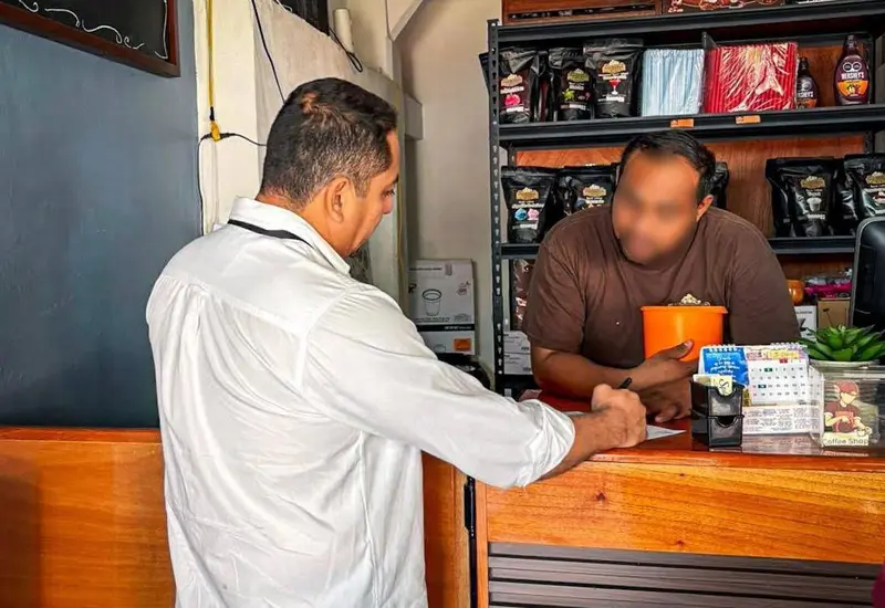 Un funcionario revisa la licencia sanitaria de un comercio en Juchitán, documento que garantiza el cumplimiento de las normas de higiene.