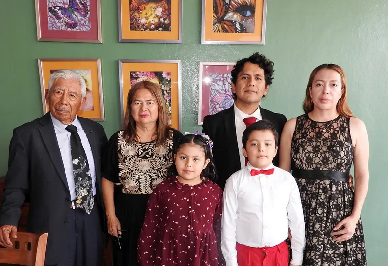 El doctor Adalid Juan Osorio celebra la culminación de su especialidad en Ginecobstetricia, posando sonriente junto a su esposa, hijos y padres.