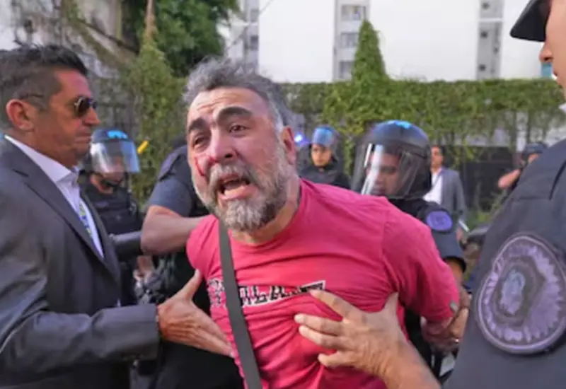 El camarógrafo Facundo Tedeschini es agredido mientras documenta con su cámara la detención de activistas de Greenpeace durante una protesta.