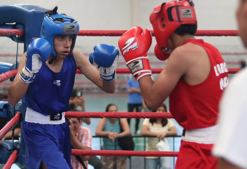 Dos jóvenes boxeadores intercambian golpes durante un aguerrido combate en el Campeonato Estatal de Boxeo, clasificatorio para el Festival Olímpico.
