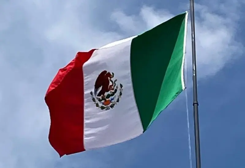 La Bandera Nacional de México, también conocida como el lábaro patrio, ondeando en conmemoración de su día oficial, un símbolo de la historia mexicana.