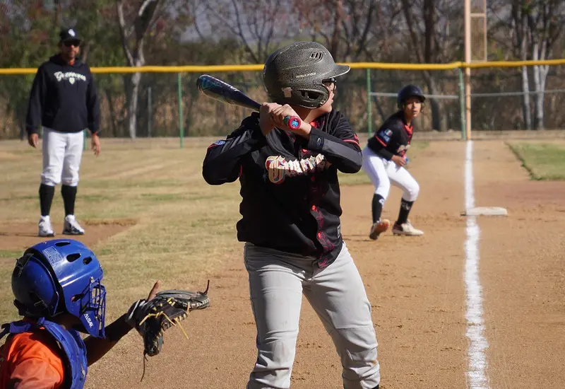 Un jugador de béisbol en plena acción durante el rally decisivo del tercer inning que resultó en una espectacular voltereta en el marcador.