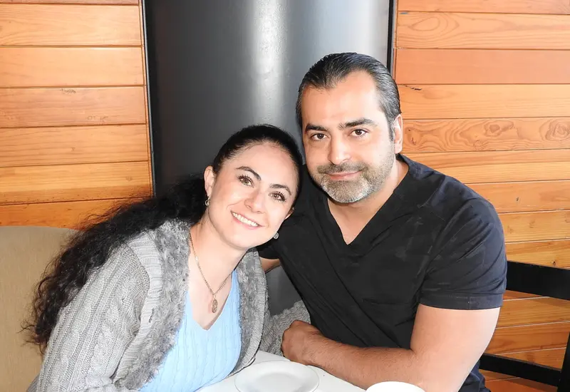 Jenny Kaminski y Hugo Castro posan juntos y sonríen para la cámara mientras disfrutan de un café en un evento social.