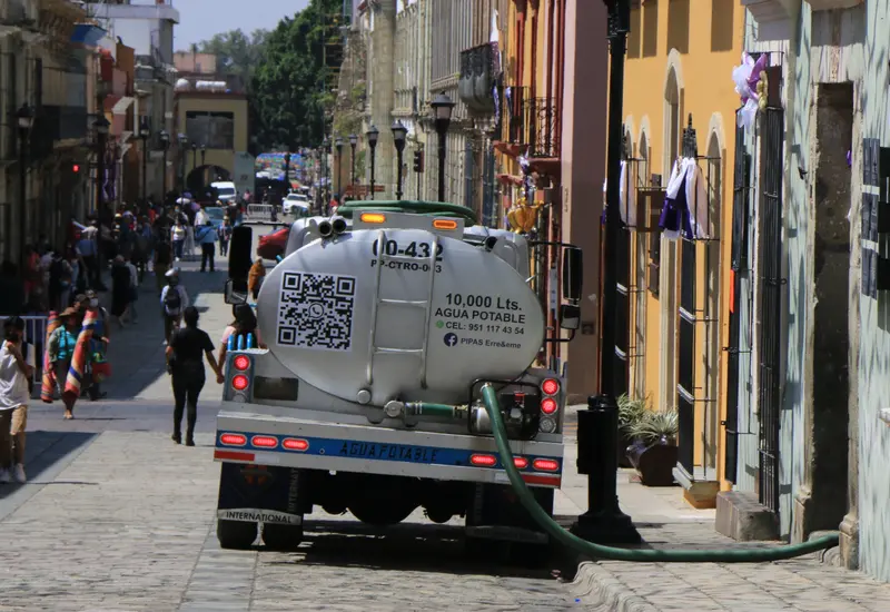 Una pipa de agua abastece a vecinos durante el estiaje, reflejando el aumento de precios por la escasez de agua en la ciudad.
