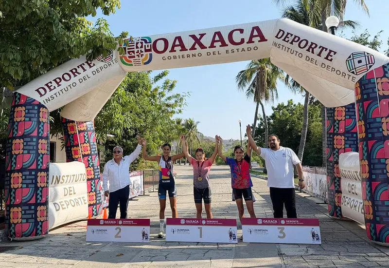 Las tres atletas ganadoras de los primeros lugares en la rama femenil del duatlón posan juntas en el podio de premiación.