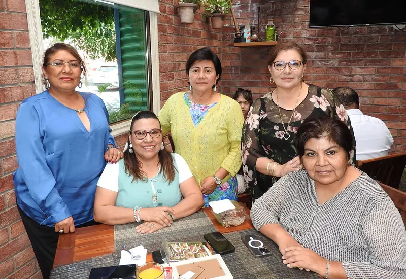 La abogada Araceli Pinelo López celebra su cumpleaños en un desayuno, sonriendo sentada a la izquierda junto a sus colegas y amigas.