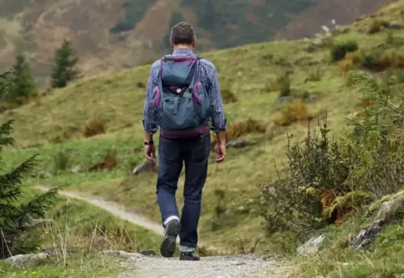 Una persona caminando al aire libre, lo cual es recomendado por expertos para cumplir la meta de 8 mil a 10 mil pasos diarios.