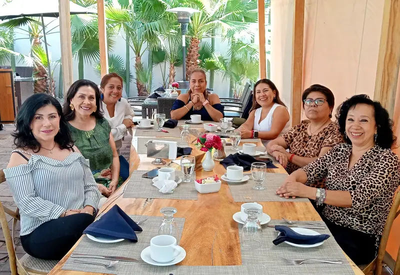 Mónica Yáñez celebra su cumpleaños en un restaurante de Oaxaca, sonriendo al centro y rodeada por su grupo de amigas cercanas.